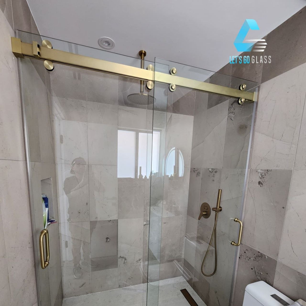 Sliding glass shower door with gold track hardware