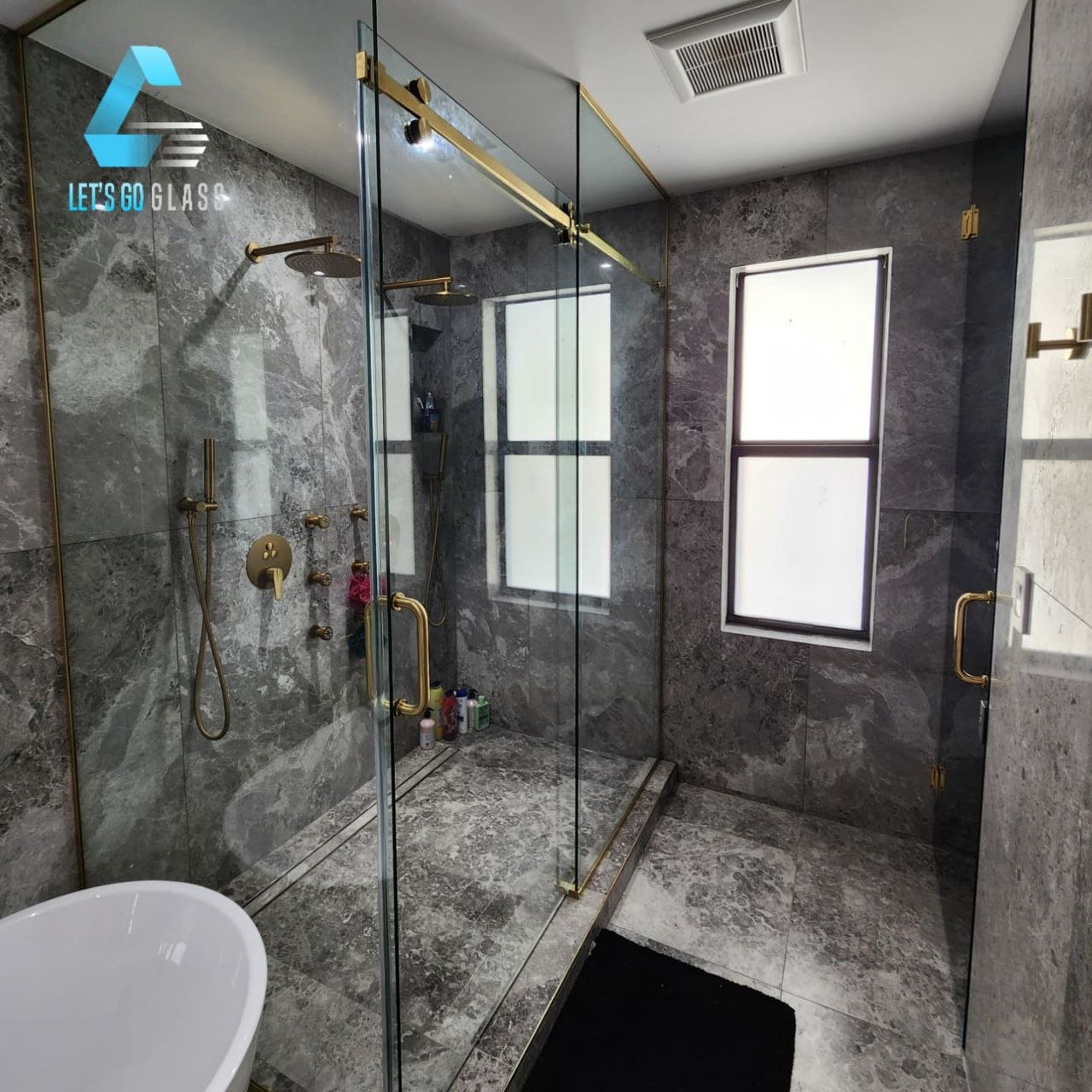 Frameless glass shower with gold hardware, white marble